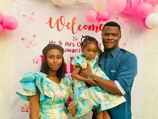 Toluwanisings in a photograph with his wife and daughter 
